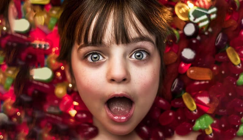 چهره دختر بچه ای بین آبنبات های رنگی