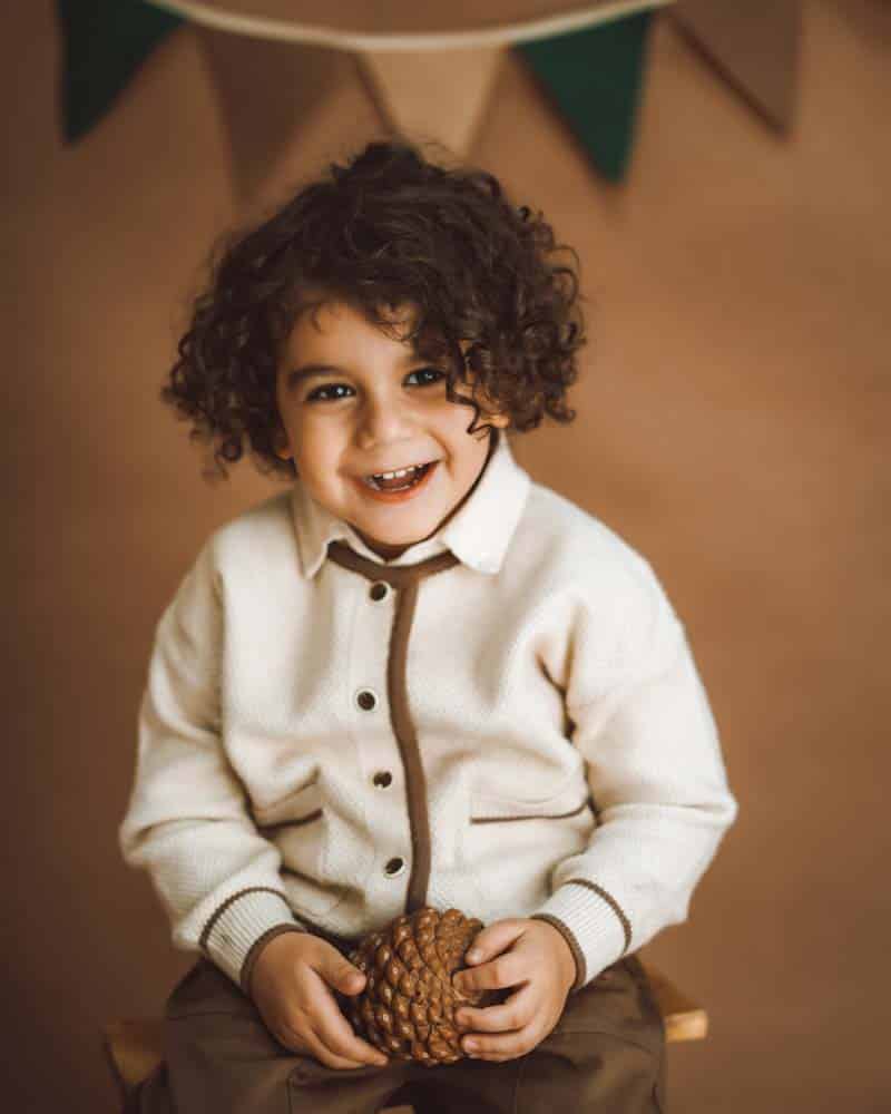 پرتره پسره بچه ای در حال خندیدن روی زمینه کرم قهوه ای
